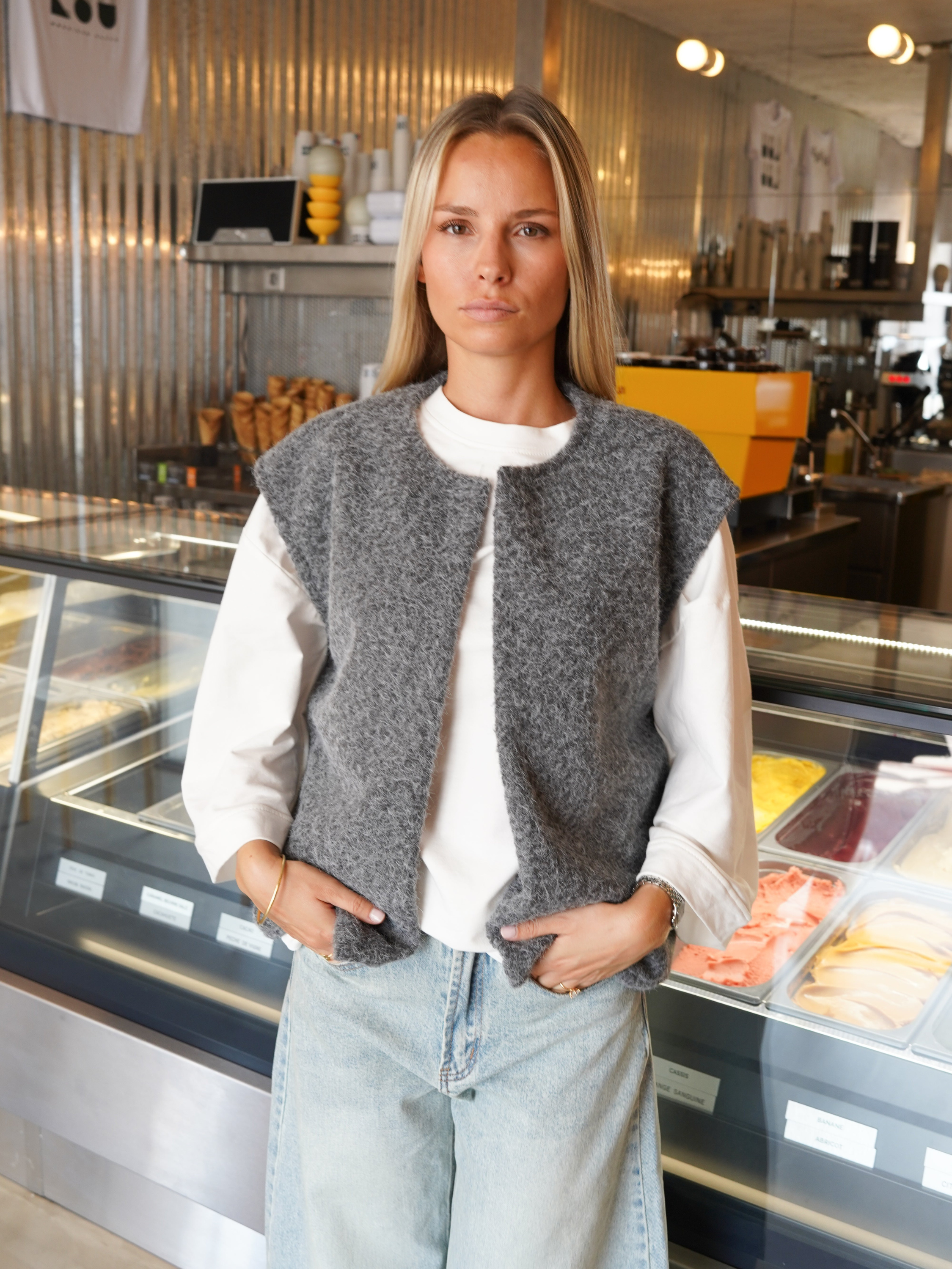Grey bouclé knit vest with jeans, model in gelato shop