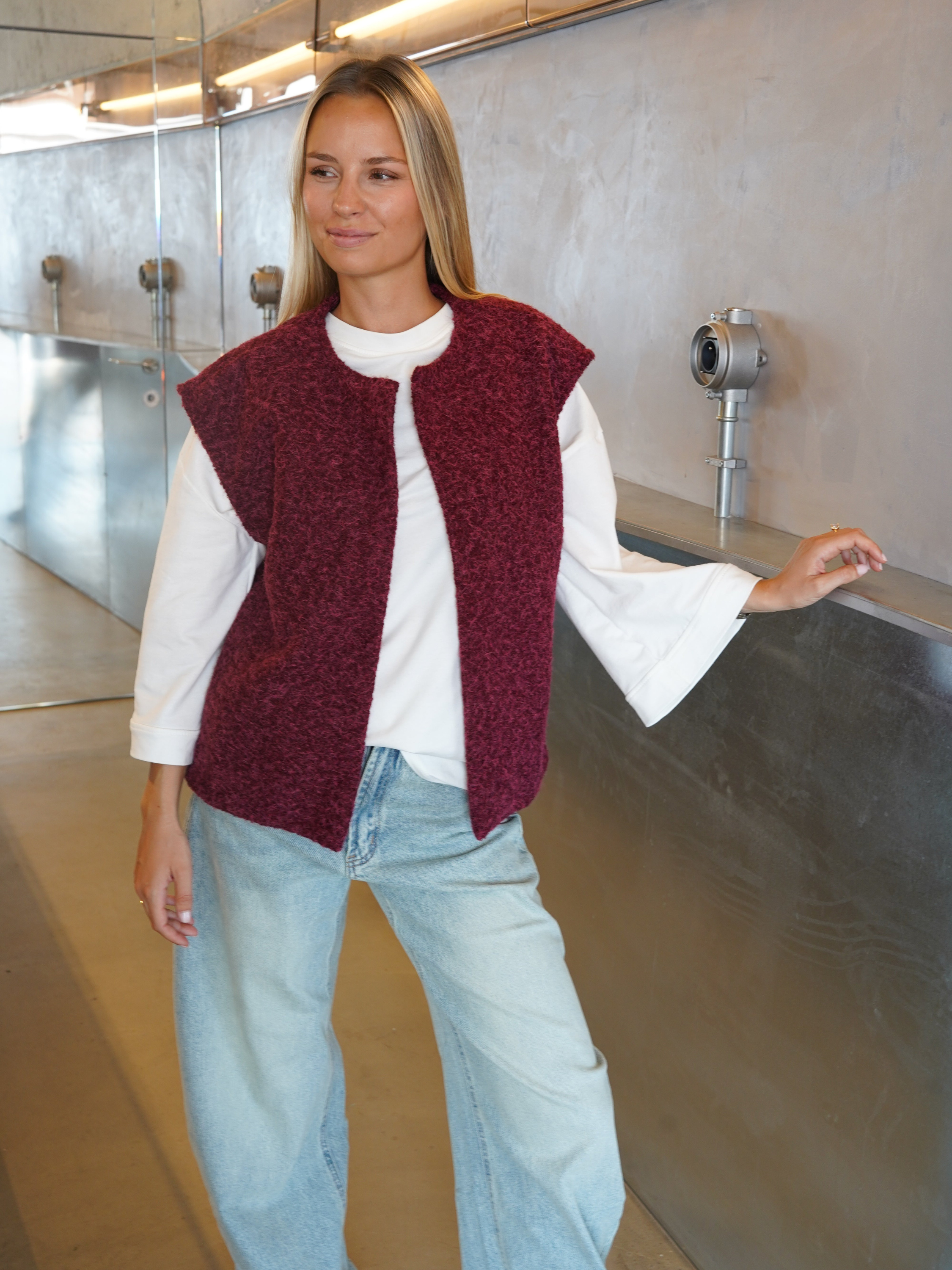 Burgundy bouclé knit vest on model, smiling side pose