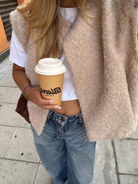 Beige bouclé knit vest over white t-shirt, close-up street style