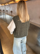 Green bouclé knit vest on model, back view with jeans