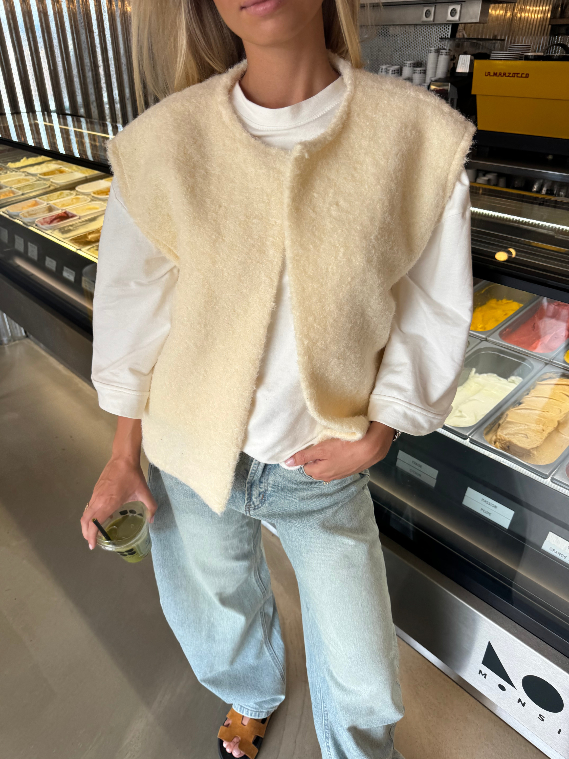 Cream bouclé knit vest over white t-shirt, close-up street style