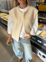Cream bouclé knit vest over white t-shirt, close-up street style