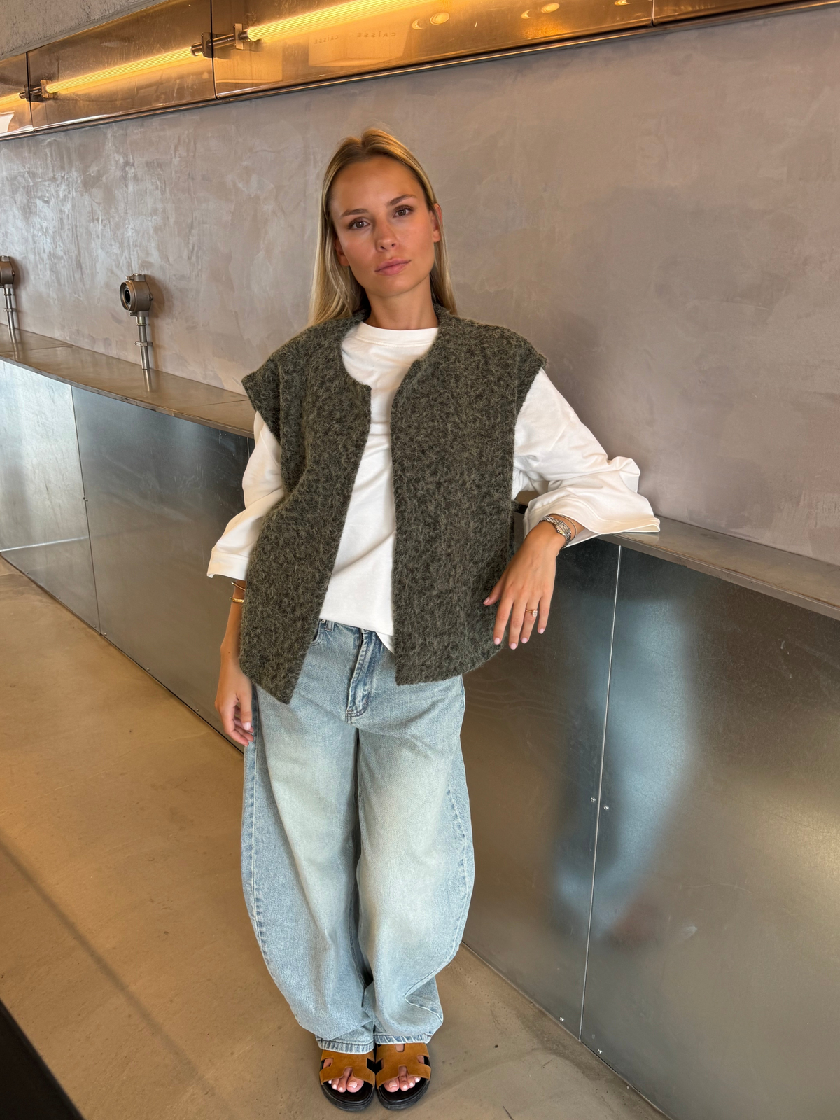 Green bouclé knit vest over white top on model, full length