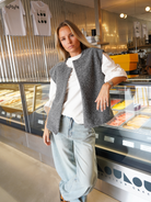 Grey bouclé knit vest on model, leaning pose in gelato shop