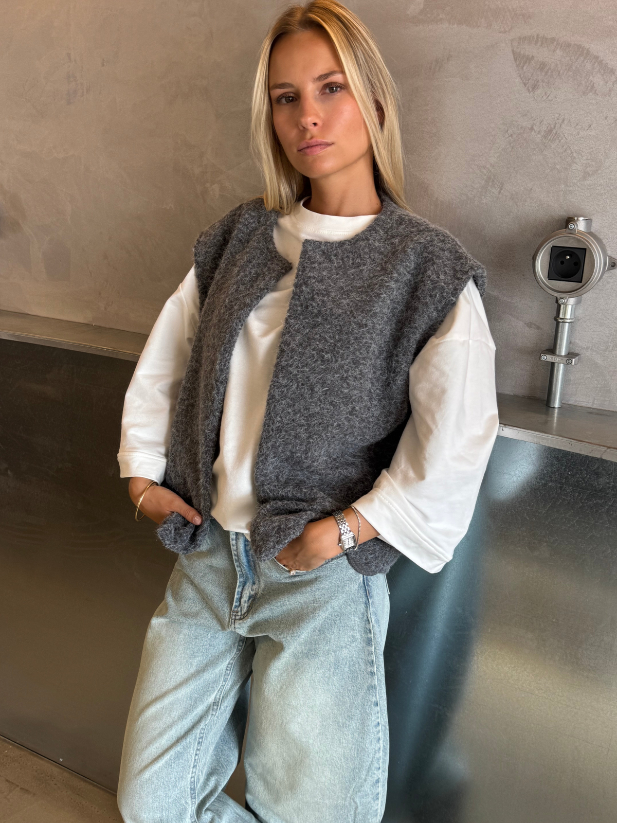 Grey bouclé knit vest over white top on model, front view