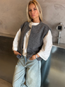 Grey bouclé knit vest over white top on model, front view
