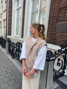 Beige bouclé knit vest over white top on model, side view outdoors