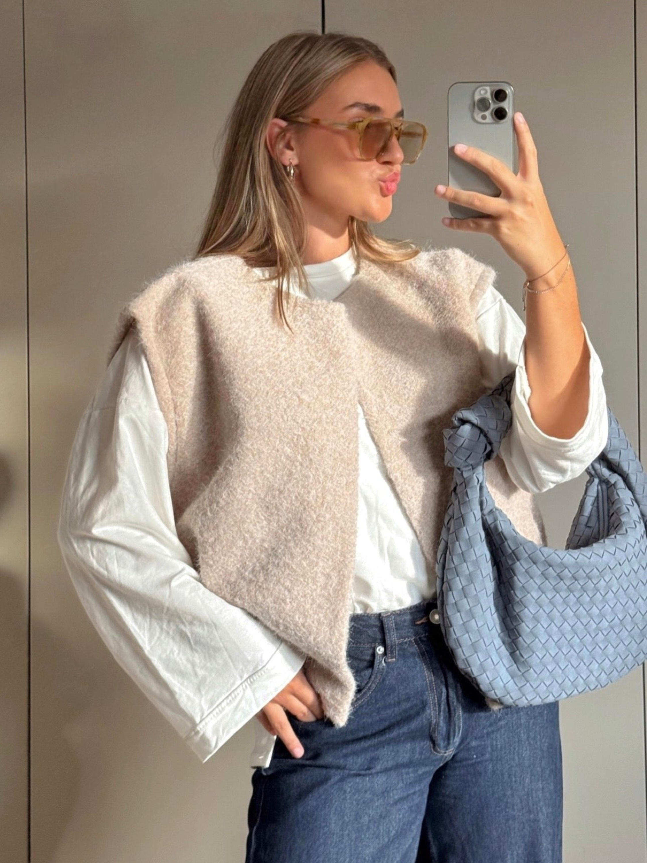 Beige bouclé knit vest over white top, mirror selfie front view