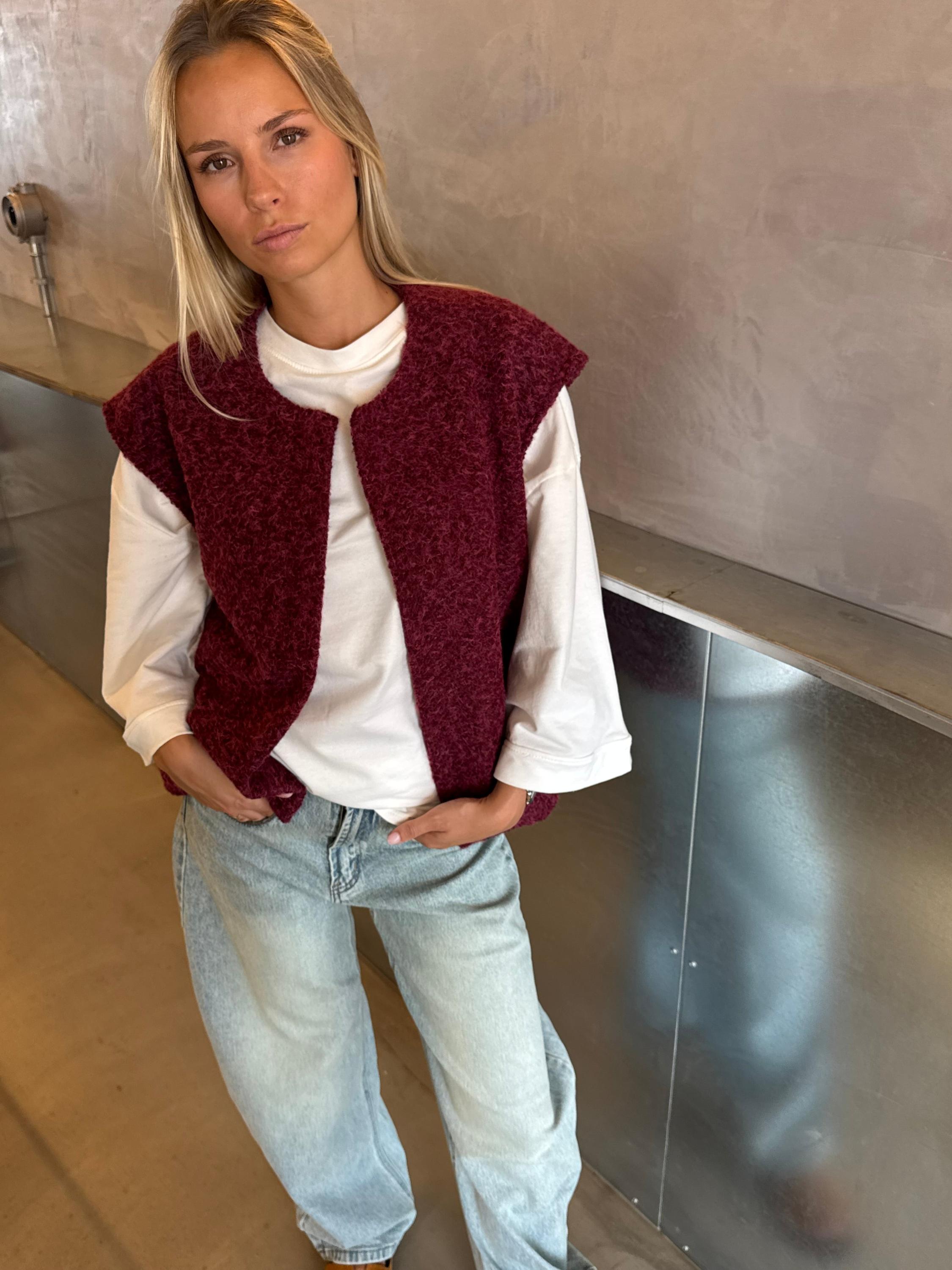 Burgundy bouclé knit vest on model, close crop with jeans