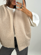Close-up of beige bouclé knit texture and open vest front