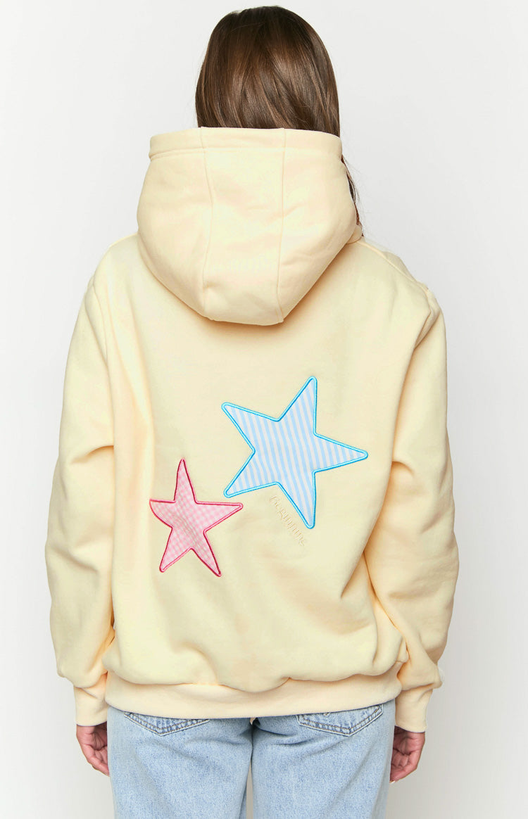 Cream hoodie with star patches, back view on model, studio shot