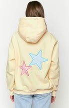 Cream hoodie with star patches, back view on model, studio shot