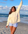 Cream oversized hoodie with star patches, front view on beach