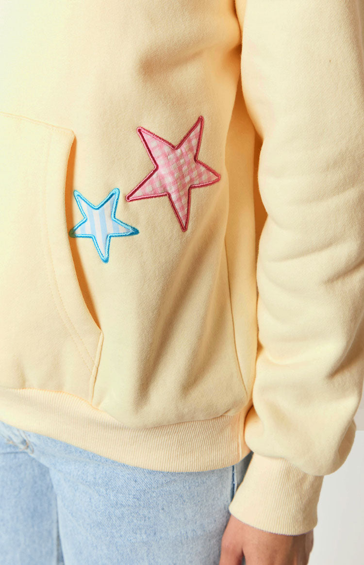 Close-up of cream hoodie pocket with gingham star patches