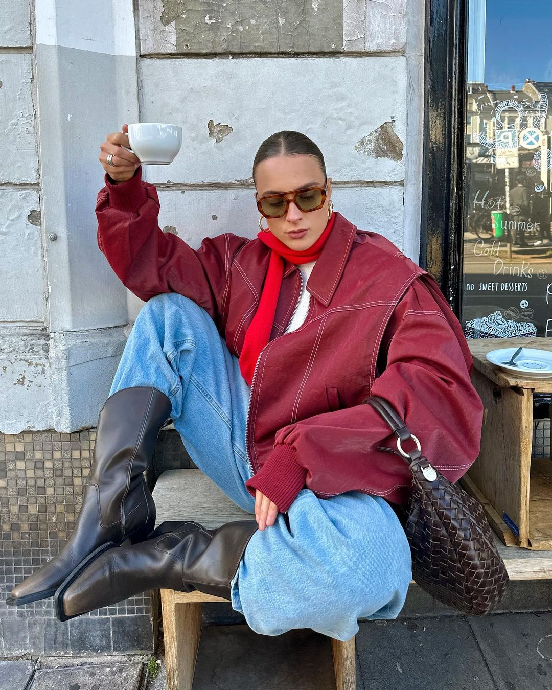 Red oversized contrast-stitch jacket over jeans, seated front view
