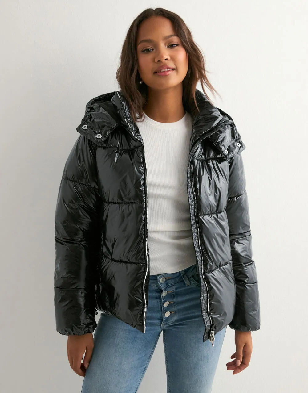 Black glossy hooded puffer jacket, front view unzipped on model
