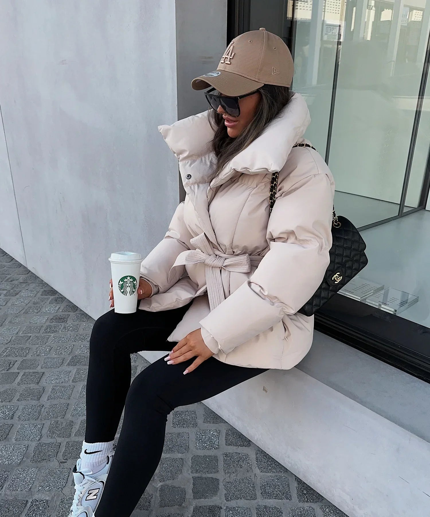Oatmeal belted puffer jacket, seated lifestyle shot on model