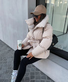 Oatmeal belted puffer jacket, seated lifestyle shot on model