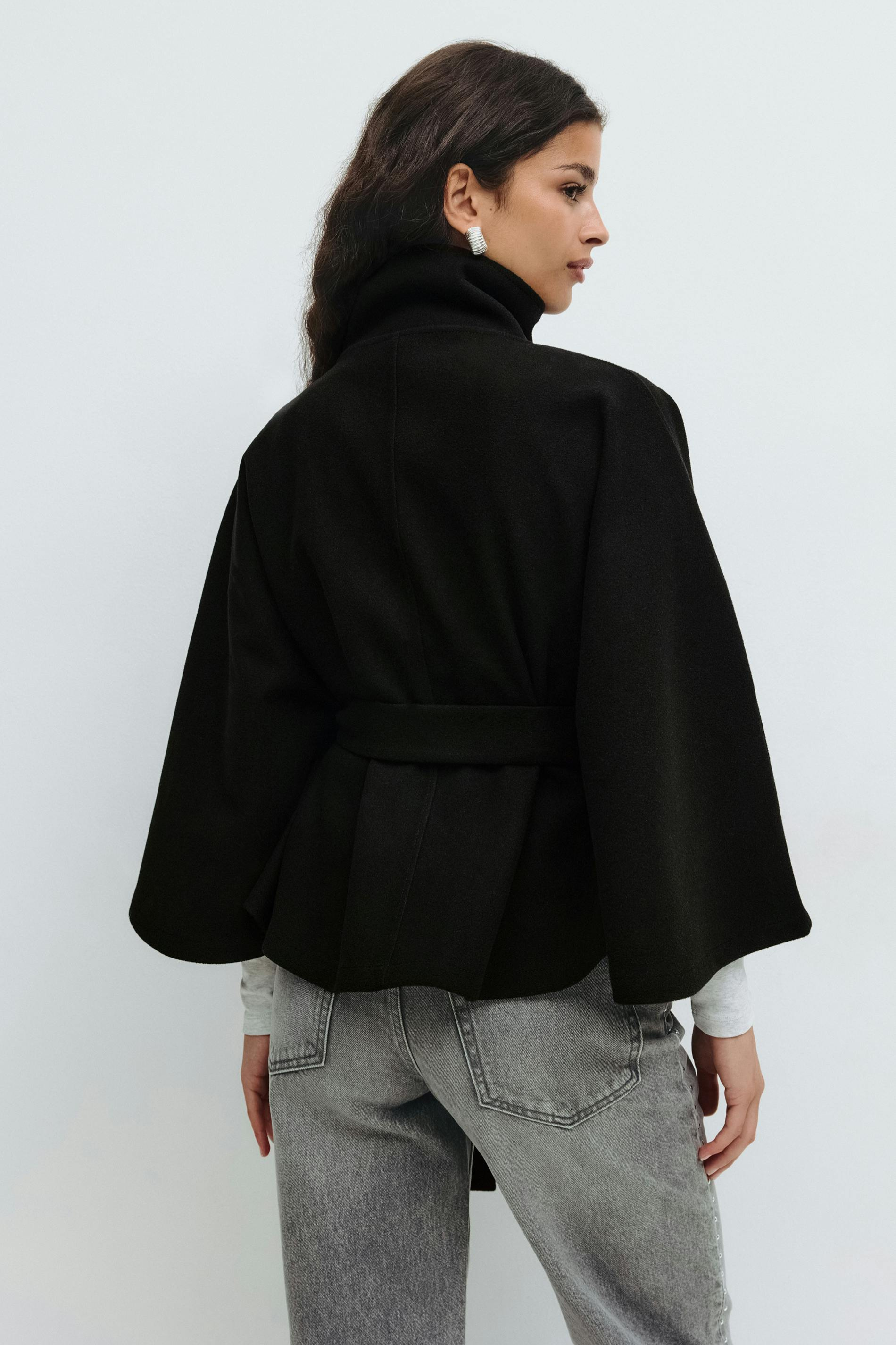Black belted cape jacket, back view on model