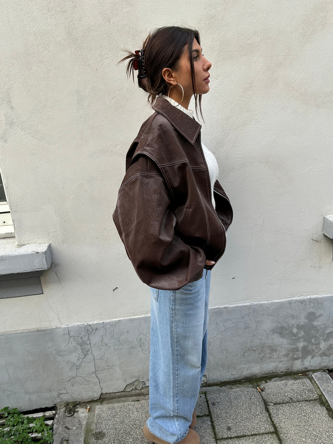 Brown oversized contrast-stitch jacket, side view against wall