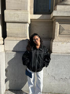 Black oversized contrast-stitch jacket over white trousers, front view