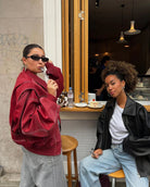 Red oversized contrast-stitch jacket, side view with friend at cafe