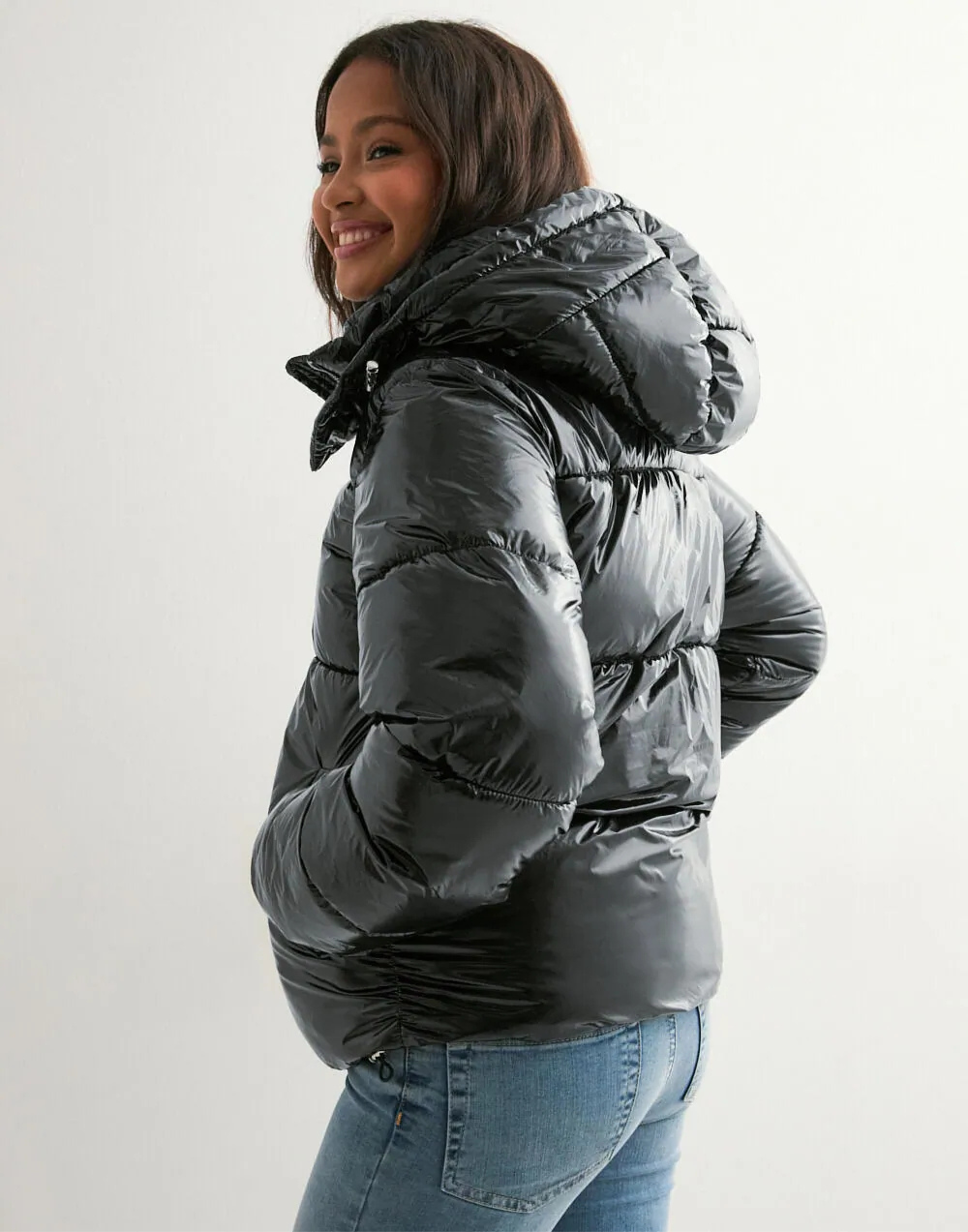 Black glossy hooded puffer jacket, side view on model