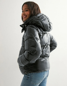 Black glossy hooded puffer jacket, side view on model
