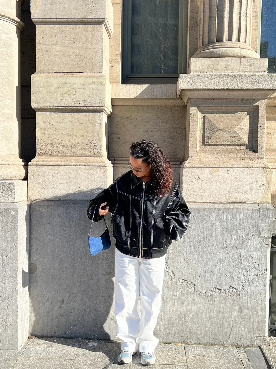 Black oversized contrast-stitch jacket over white trousers, front view looking down