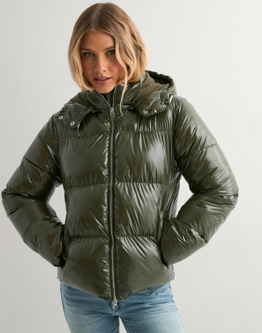 Close-up of green glossy hooded puffer jacket on model
