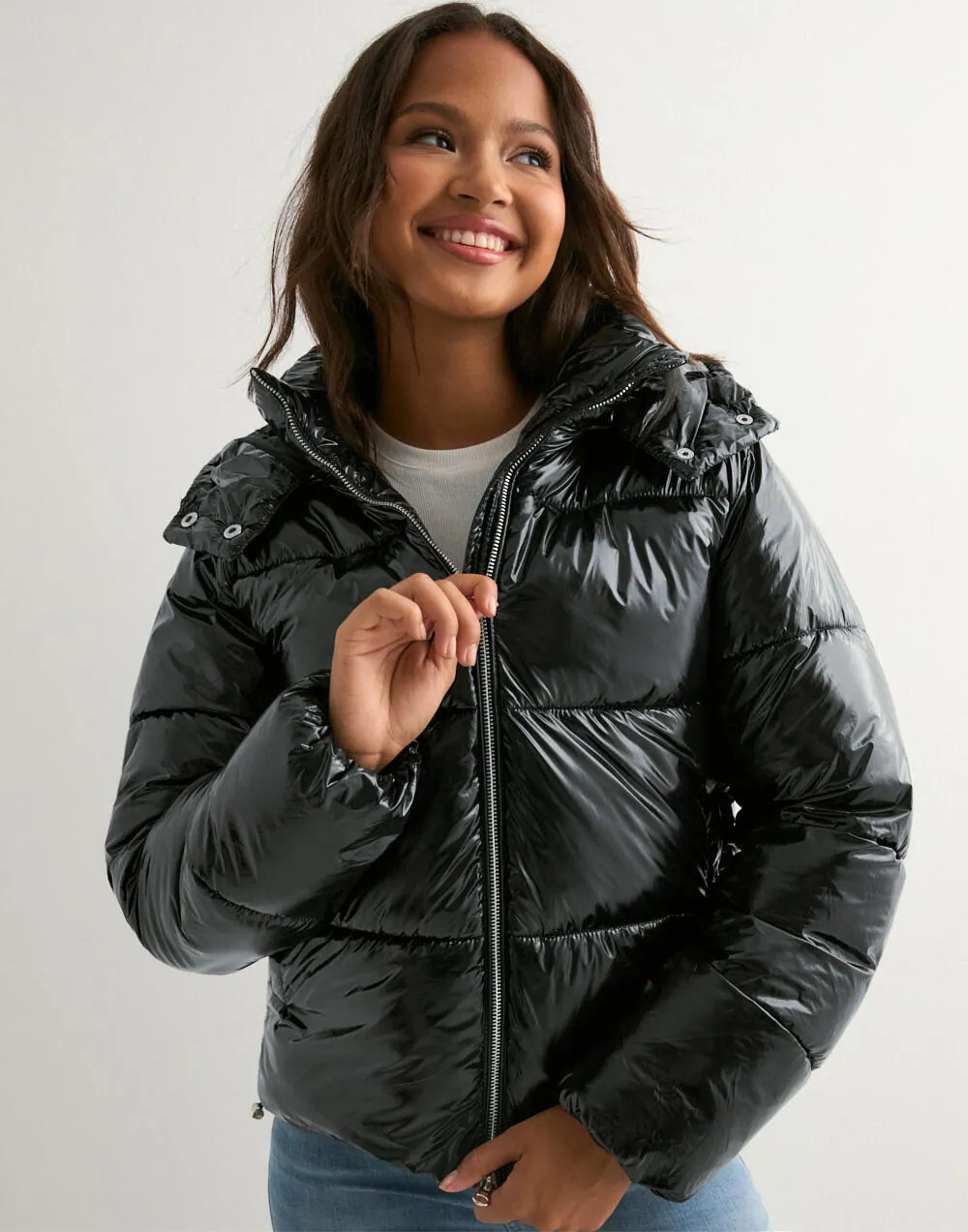 Close-up of black glossy hooded puffer jacket on model
