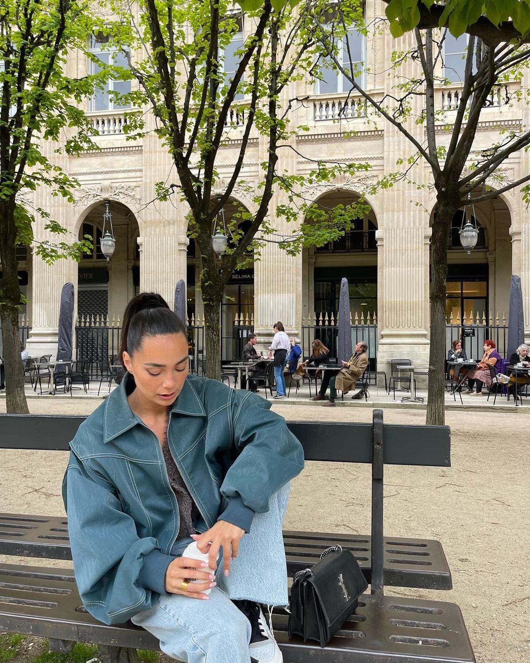 Deep green oversized contrast-stitch jacket, seated front view on bench