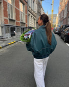 Deep green oversized contrast-stitch jacket, back view holding flowers