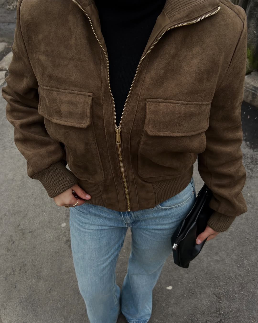 Close-up of brown suede bomber jacket with flap pockets on model