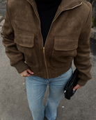 Close-up of brown suede bomber jacket with flap pockets on model