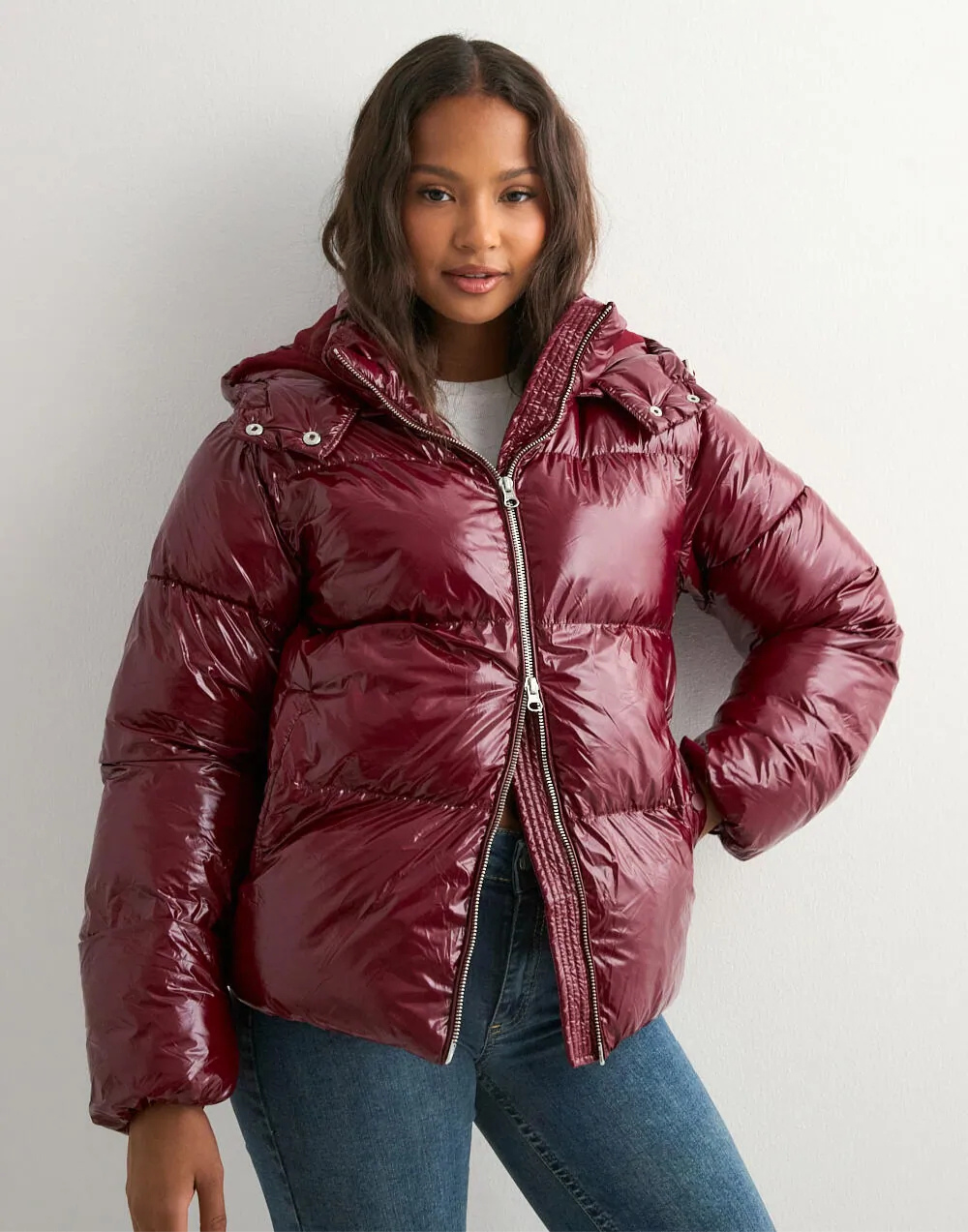 Close-up of wine red glossy hooded puffer jacket on model