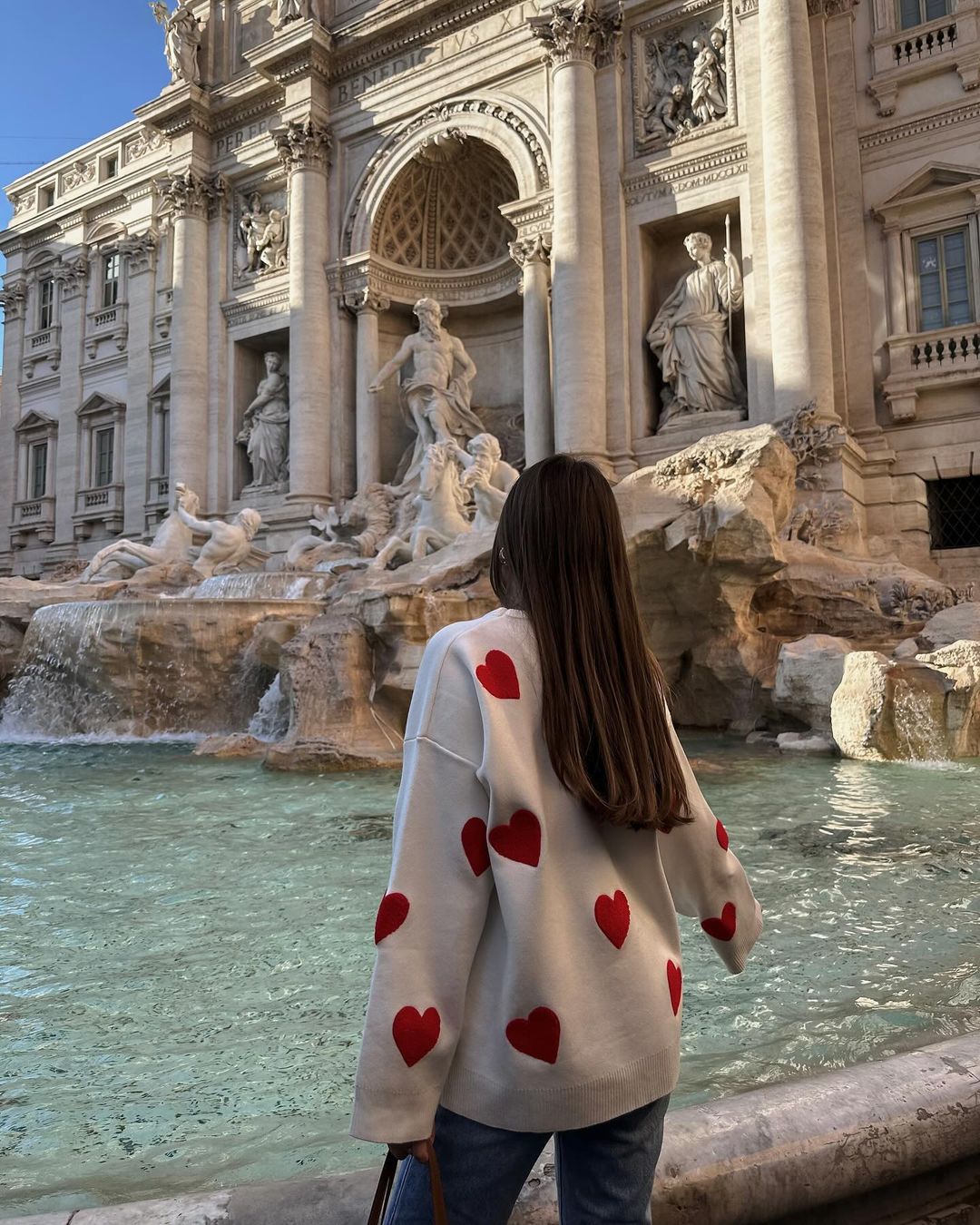 Ivory jumper with red heart print, back view facing fountain