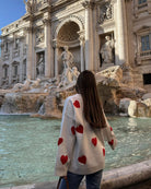 Ivory jumper with red heart print, back view facing fountain