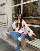 Ivory jumper with red heart print, front view on seated model