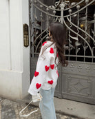 Ivory jumper with red heart print, side view on model at gate