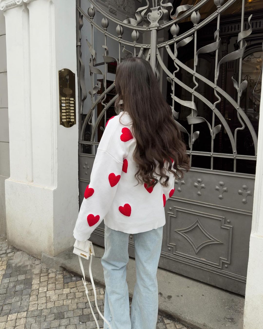 Ivory jumper with red heart print, back view on model at gate