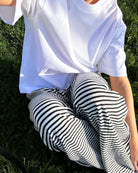 Black and white striped wide-leg trousers, close-up detail on model