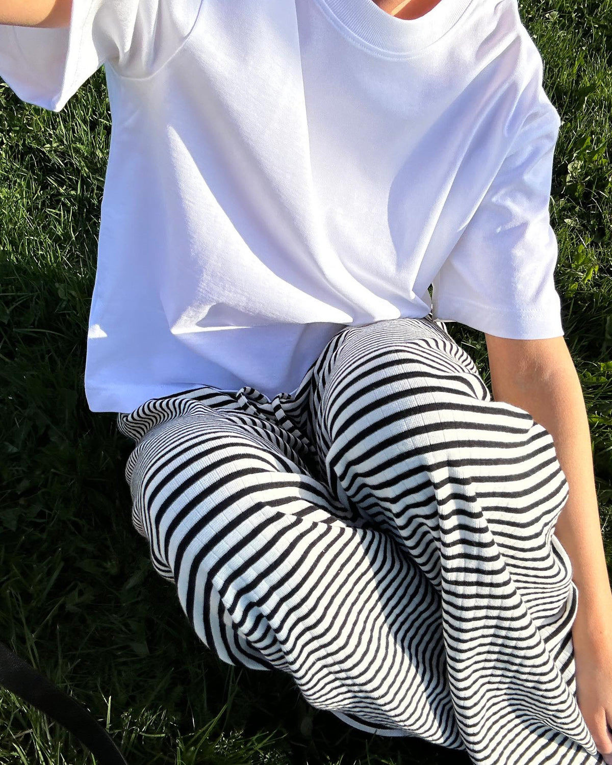 Black and white striped wide-leg trousers, close-up detail on model