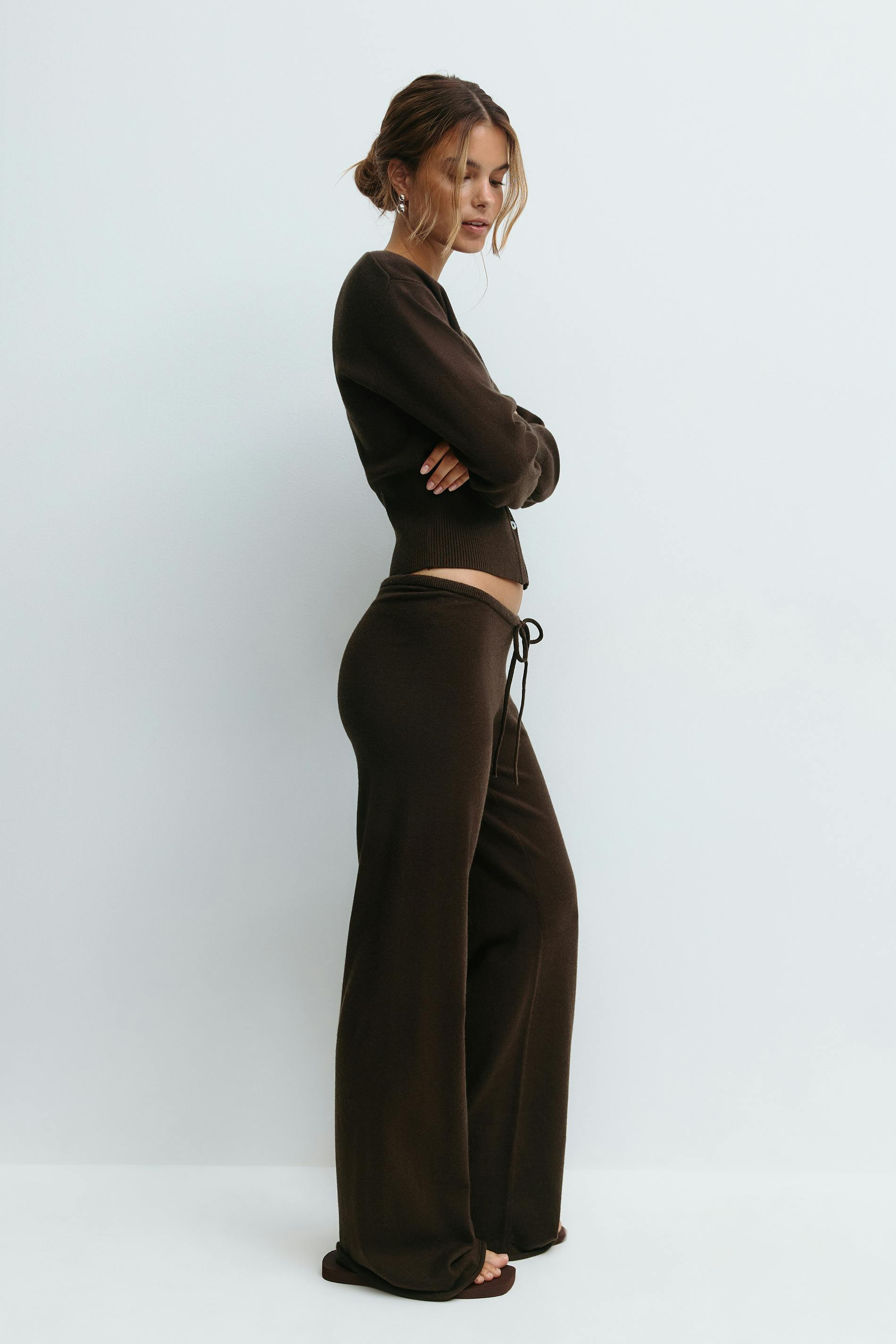 Brown knitted cardigan and trousers set on model, side view