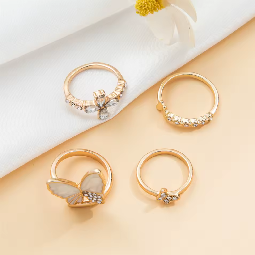 Gold butterfly ring set, four rings flat lay on white fabric