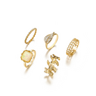 Golden five-piece ring set with leaf and stone details, flat lay