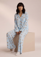 Light blue breakfast-print pyjama set, model seated on plinth
