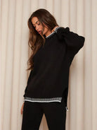 Close-up of black jumper with white whipstitch trim on model