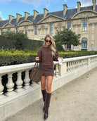 Brown cropped jacket and mini skirt two-piece set, front view by balustrade