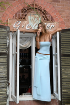 Mist blue corset top and wrap maxi skirt, model leaning out of window